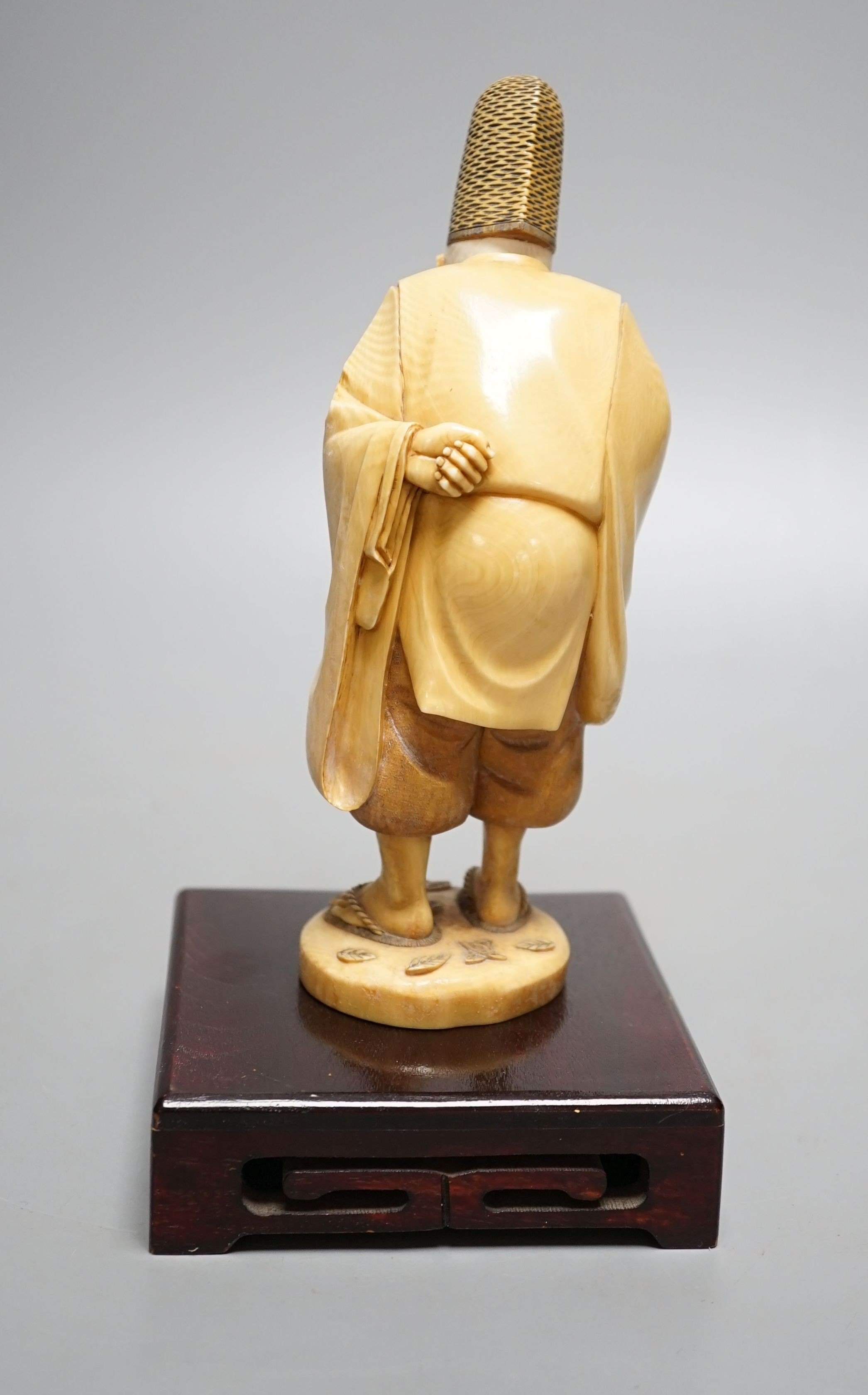 A Japanese ivory figure of a court official, wearing a tall eboshi hat, Taisho period, signed to a lacquer tablet - 18.5cm tall